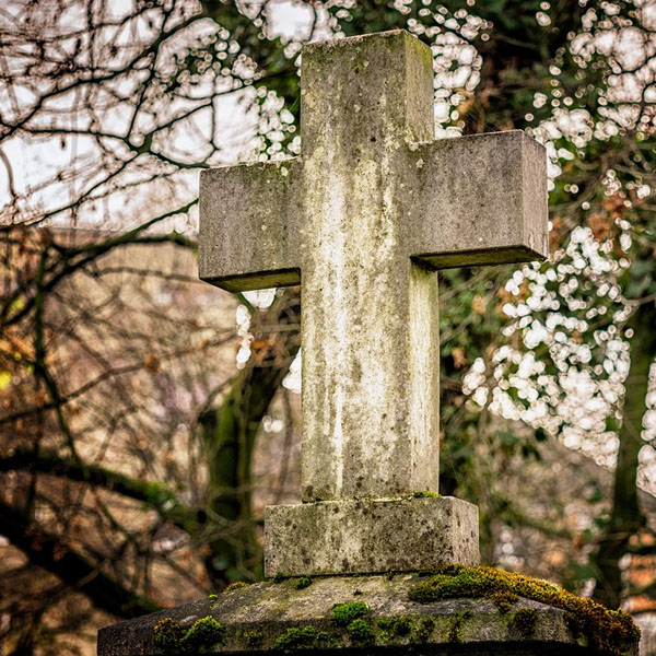 worn, moss-covered cross tombstone