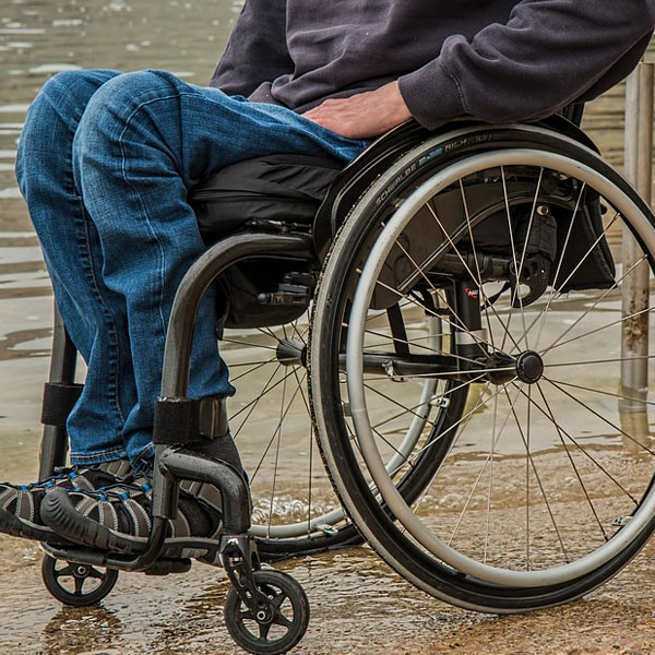 disabled man sits in wheelchair in front of a body of water