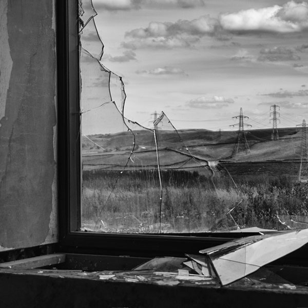 broken window and fallen, shattered glass with view of power lines in a field
