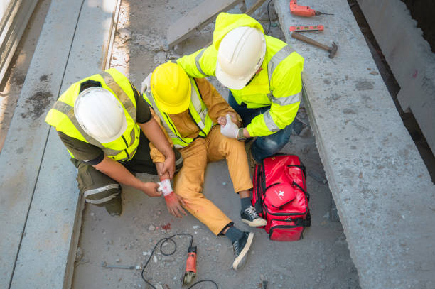 Construction worker has an accident at a construction site. Emergency help provides first aid to his injuries.