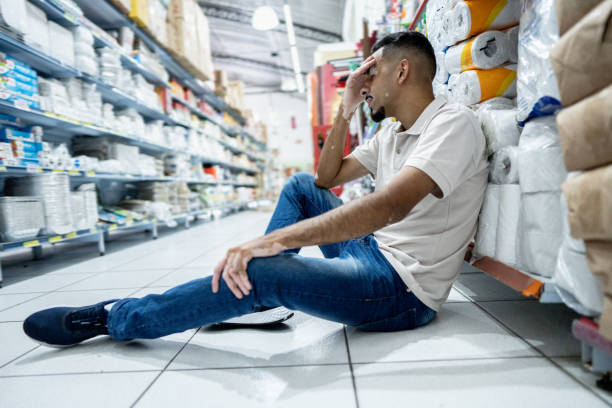 A grocery store employee sits on the ground and assesses his injury after an accident while working.