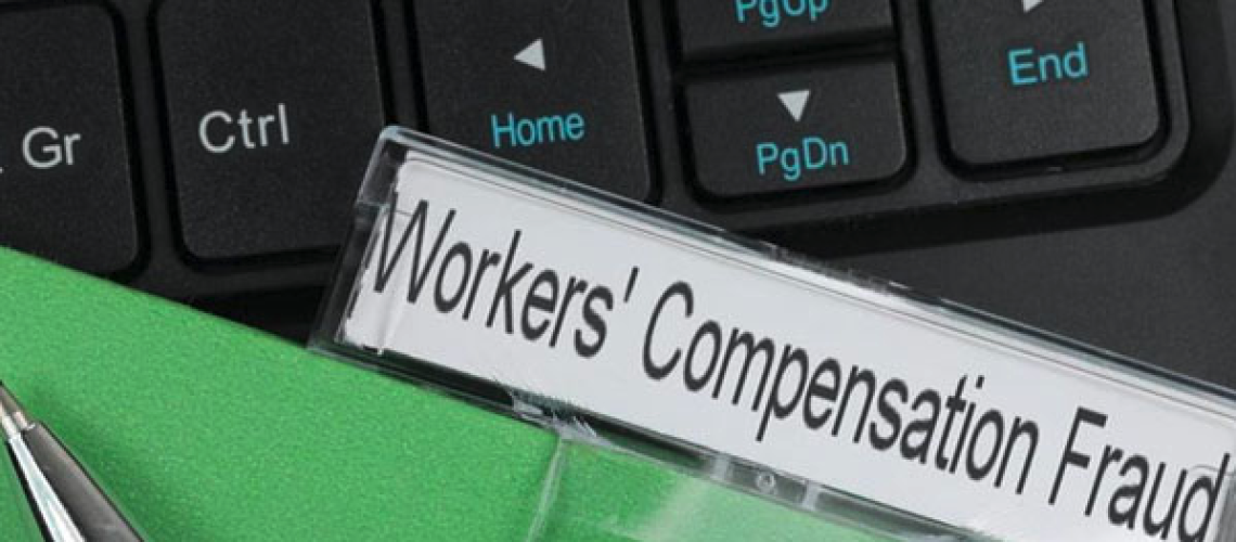 black keyboard with a green file folder labelled workers' compensation fraud on top of it