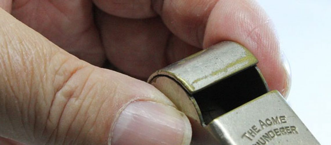 hand holding metal whistle with an engraving that reads The Acme Thunderer